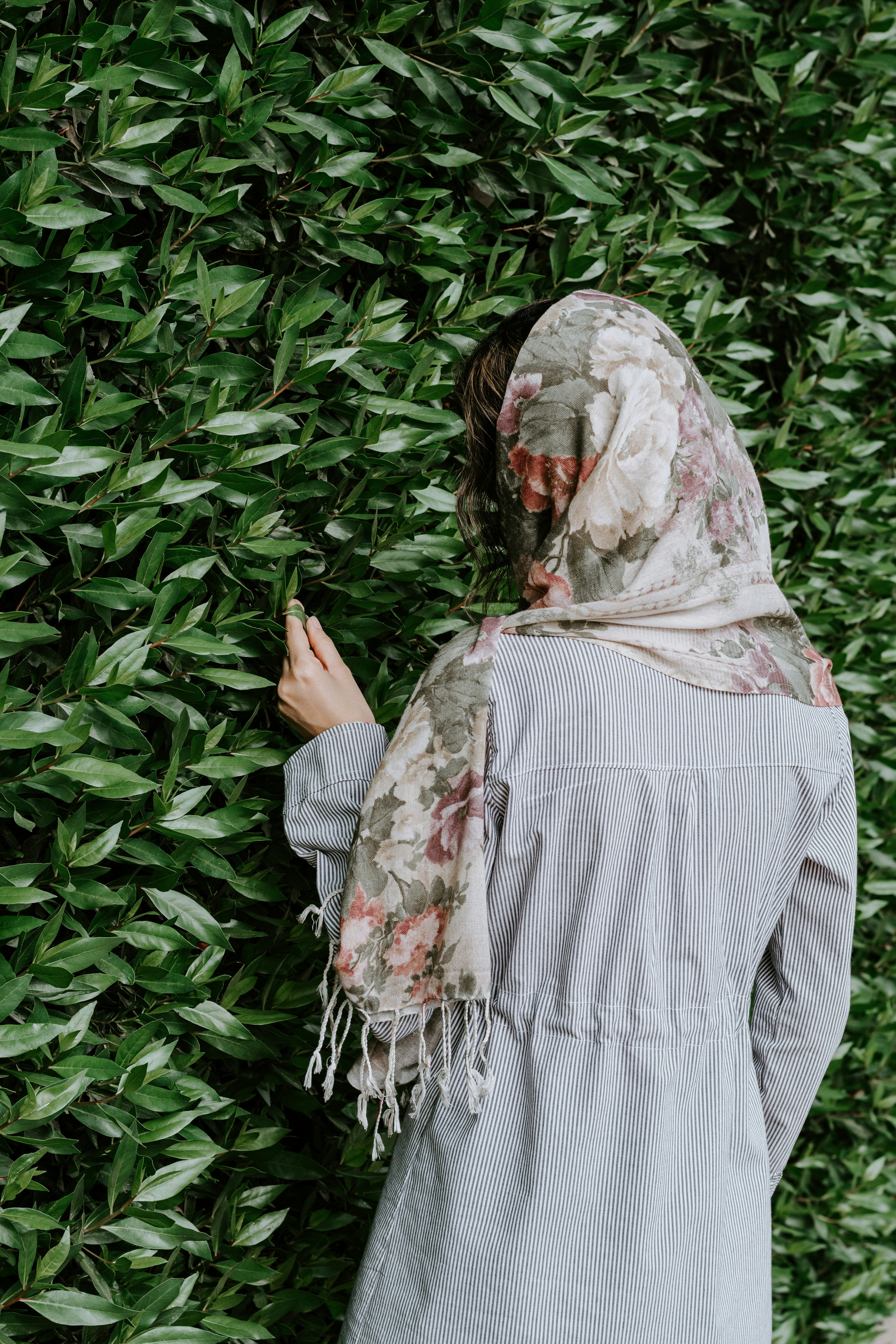 woman in white and red hijab standing near green plants